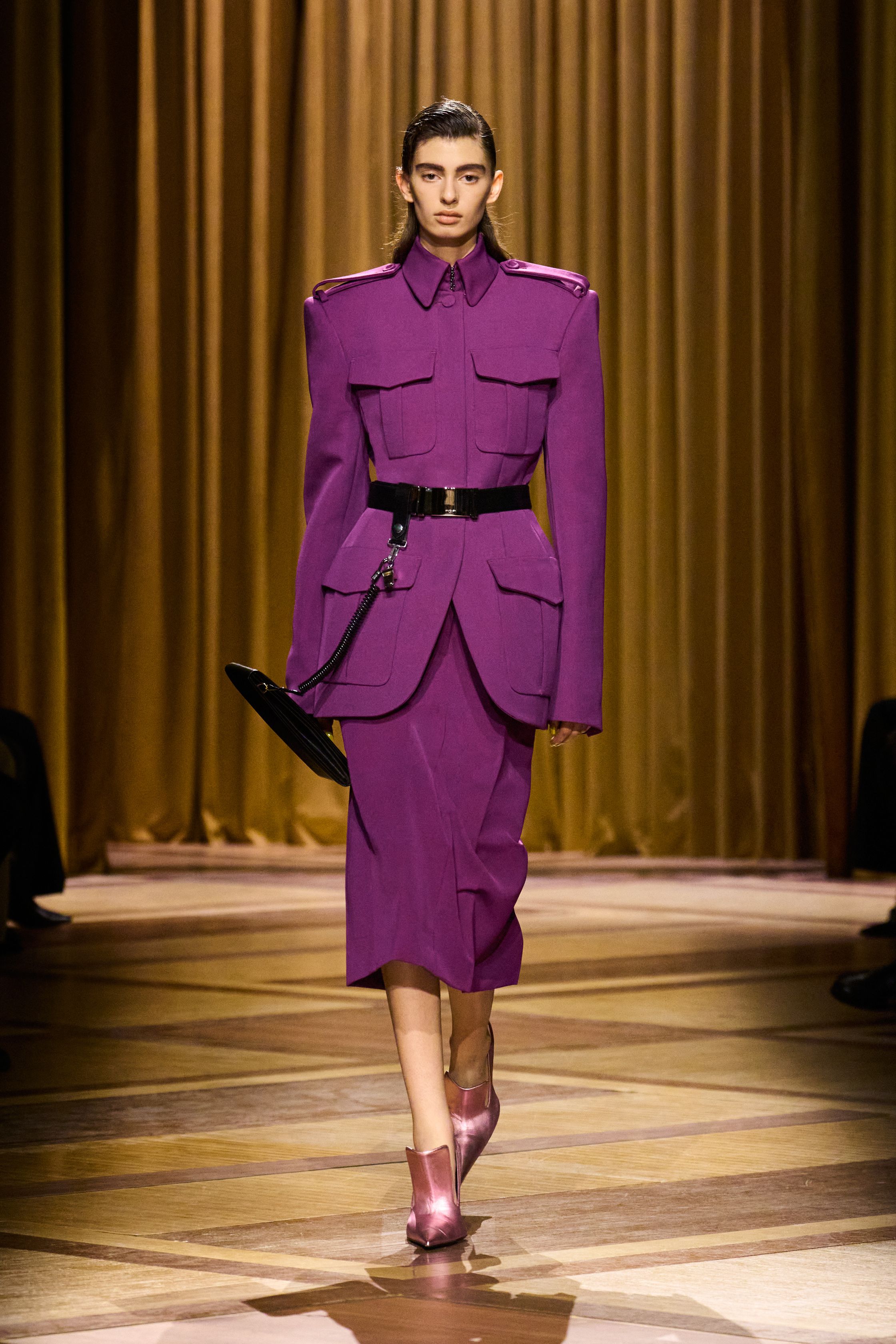 Mugler 本季继续强化品牌最核心的雕塑性感：极端肩线、收紧腰部与流畅长裤塑造出未来感女性轮廓。紫色权力套装、金属光泽衬衫和皮革裙装让整场秀既强势又华丽，仿佛科幻电影中的都市女主角-顽石频道趋势研究